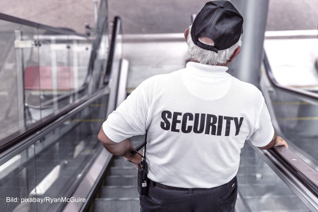 Ein Security-Mitarbeiter am Flughafen auf der Rolltreppe. Symbolbild für Lohnverhandlungen Sicherheitspersonal.